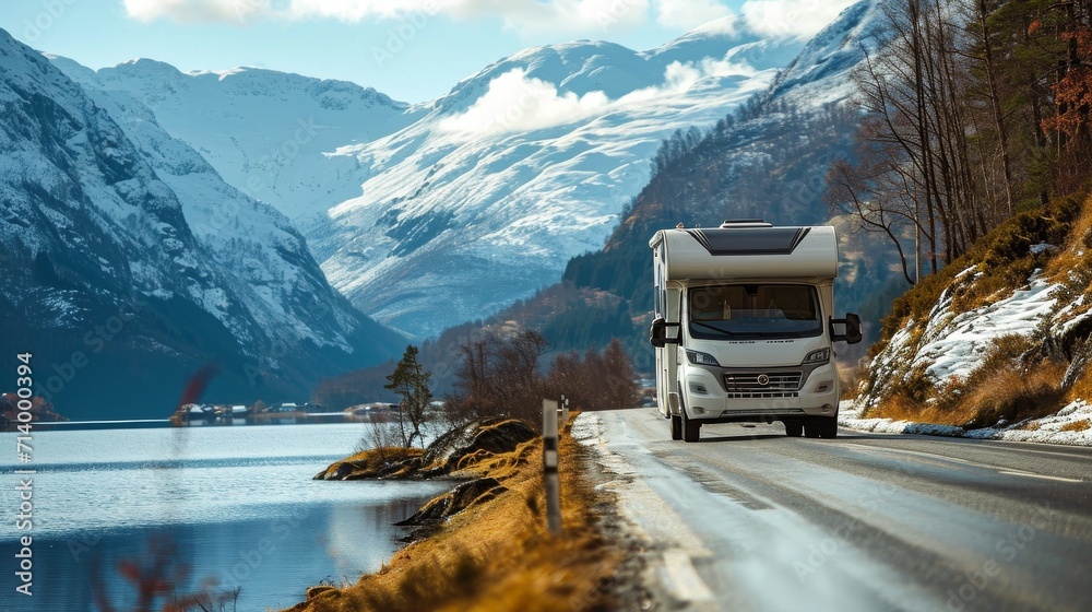 Modern motorhome driving on road with views of lake and mountains in background