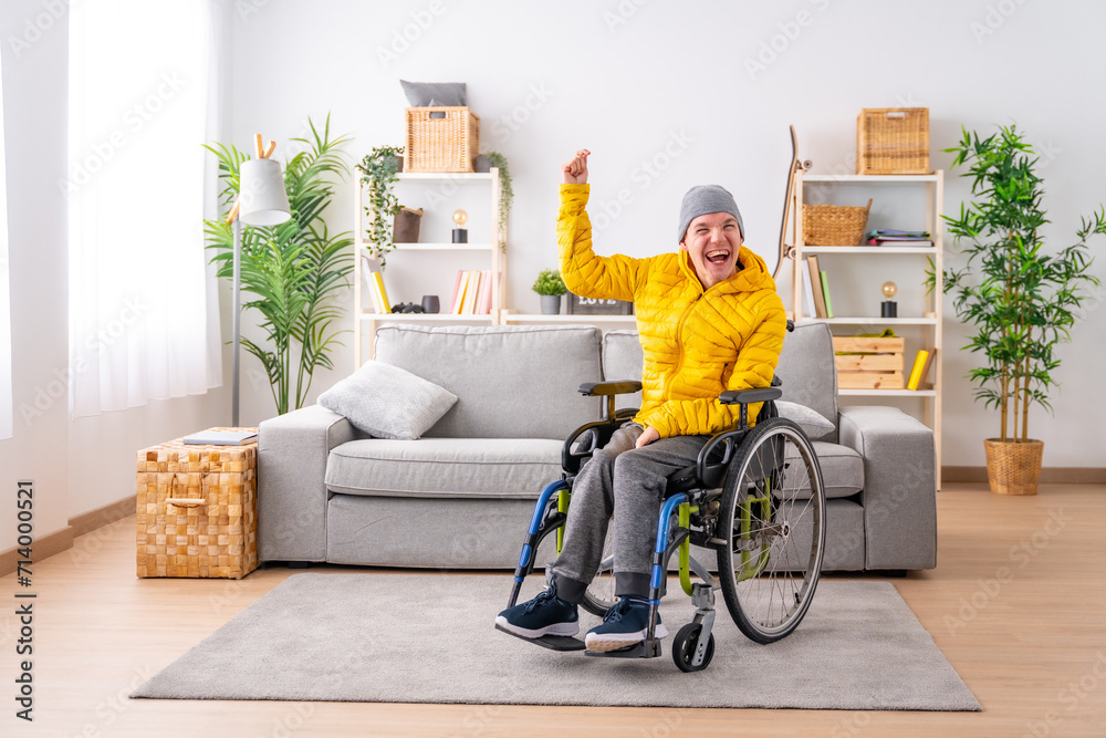 Disabled man in wheelchair celebrating raising fist at home Disabled man in wheelchair celebrating raising fist at home