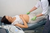 Gynecologist measuring smiling pregnant woman with obstetric pelvis gauge