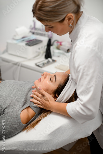 Cosmetologist performs a hand massage in the neck area of a client © fesenko