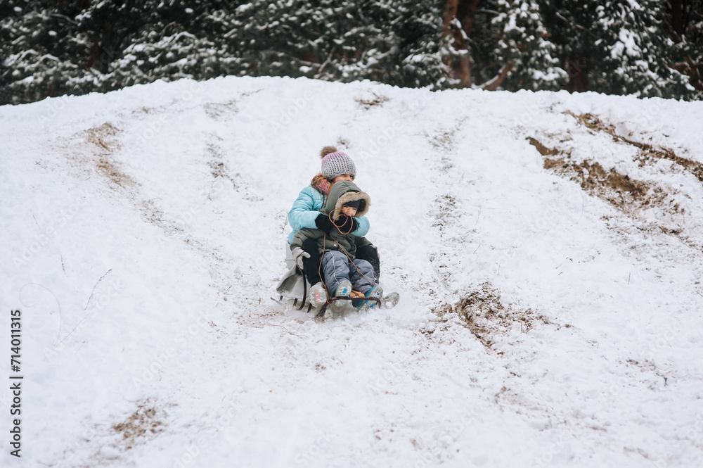 A little boy with a girl sister, happy children, family sledding, going down a hill in the snow in winter. Photography, portrait, childhood concept, lifestyle.