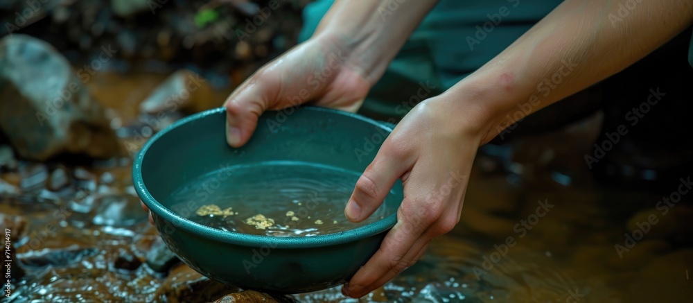 Obraz premium Youthful hands panning for gold with a green pan.