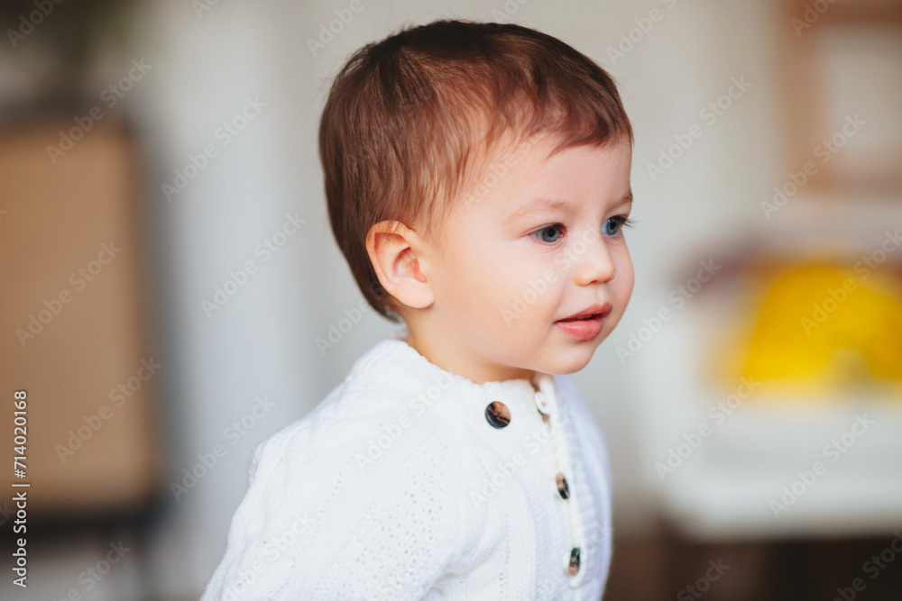 Adorable dreamy little boy toddler with blue eyes standing indoors Adorable dreamy little boy toddler with blue eyes standing indoors