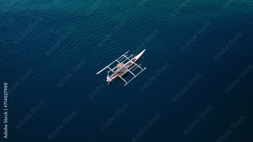 Descending aerial over fishermen on boat in deep blue open ocean.