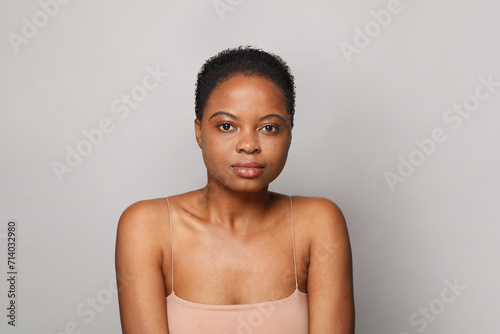 Young healthy african american woman with clear fresh dark skin posing on gray background, fashion beauty portrait