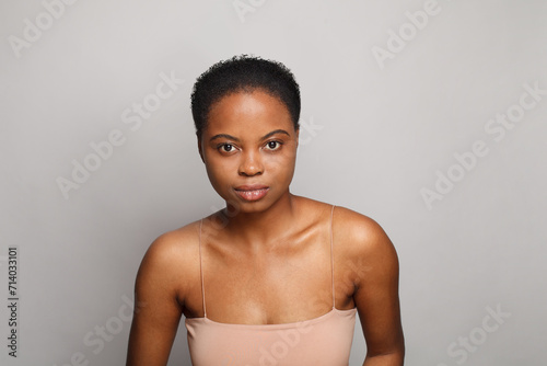 Nice healthy african american woman with clear fresh dark skin posing on gray background, fashion beauty portrait
