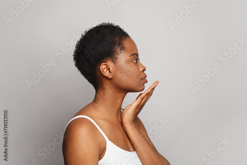 Perfect healthy african american woman with clear fresh dark skin posing on gray background, fashion beauty portrait