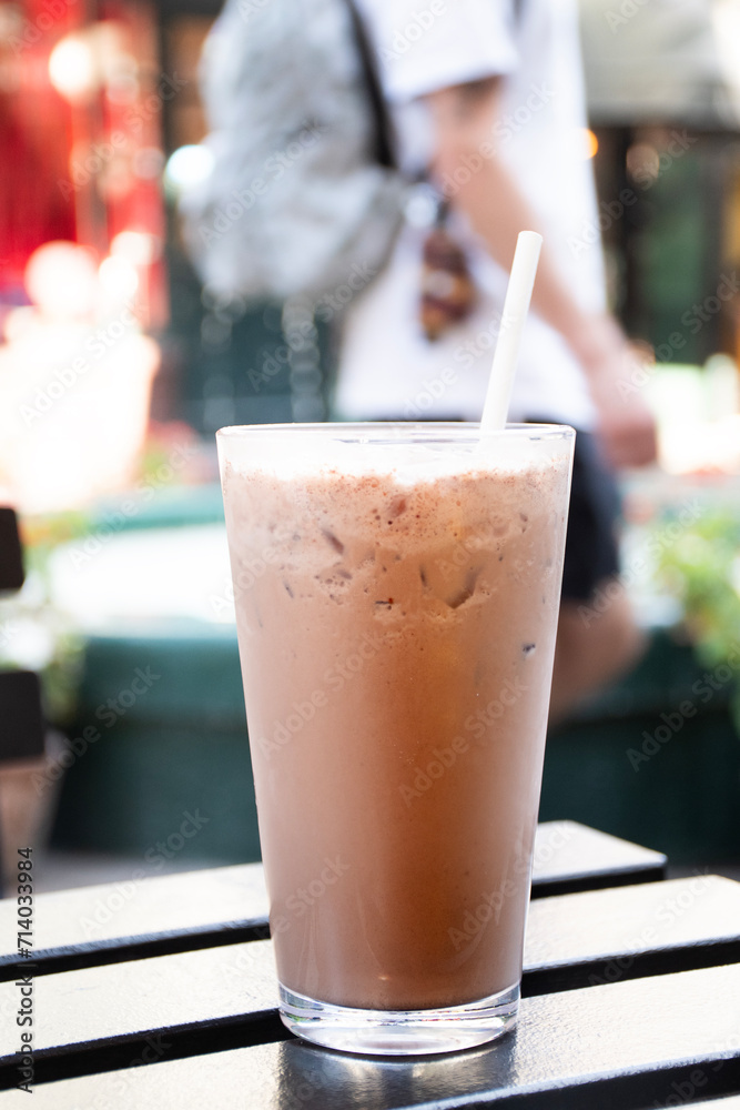 chocolate milkshake smoothie on wooden table with square flowerbed in the background chocolate milkshake smoothie on wooden table with square flowerbed in the background