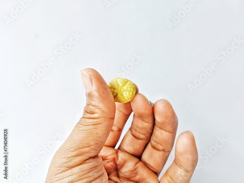 Hand holding a piece of candy  on a white background