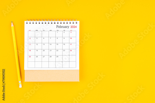 February 2024 desk calendar and wooden pencil on yellow color background.