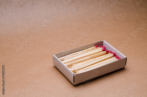 Set of new unlit matchsticks in a matchbox on natural brown paper background