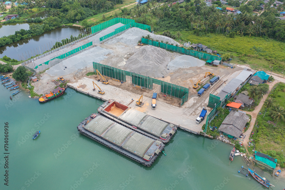 Aerial top view of concrete cement factory industry with sea. Electricity tower building in energy, transportation, logistic or environment concept. Manufacturing workshop station.