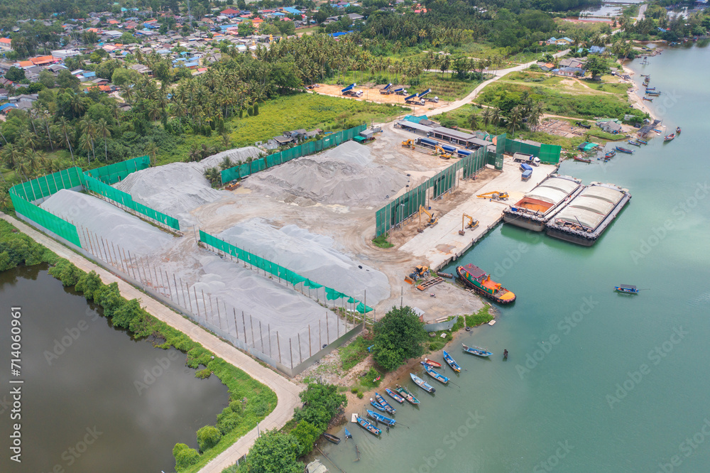 Aerial top view of concrete cement factory industry with sea. Electricity tower building in energy, transportation, logistic or environment concept. Manufacturing workshop station.