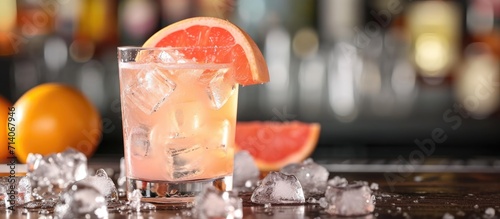 Tequila-based Paloma cocktail with grapefruit and ice on the bar counter.