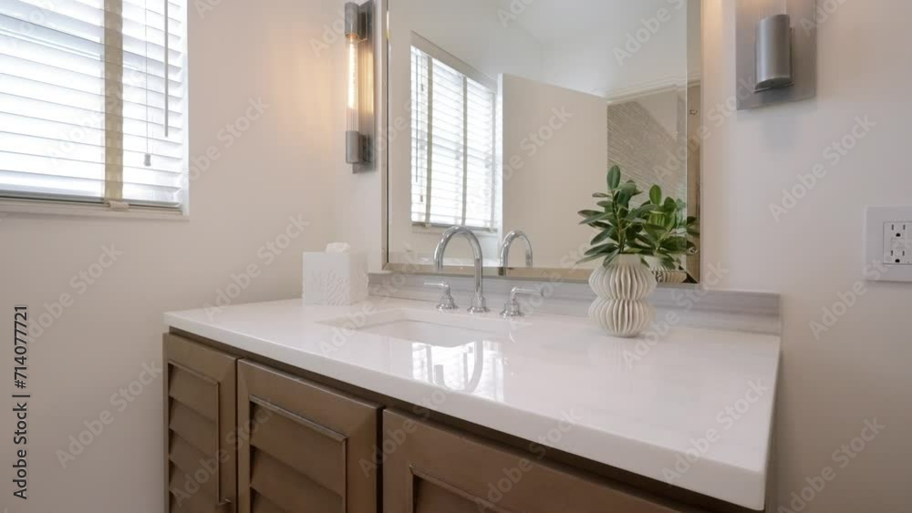 Well-lit bathroom with large rectangular mirror above sink vanity. Two modern vertical light fixtures mounted on either side of looking glass providing additional lighting Well-lit bathroom with large rectangular mirror above sink vanity. Two modern vertical light fixtures mounted on either side of looking glass providing additional lighting