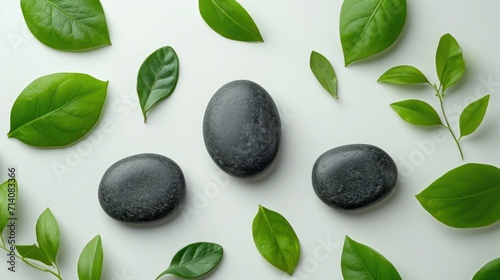 top view of three black stones and leaves on white background