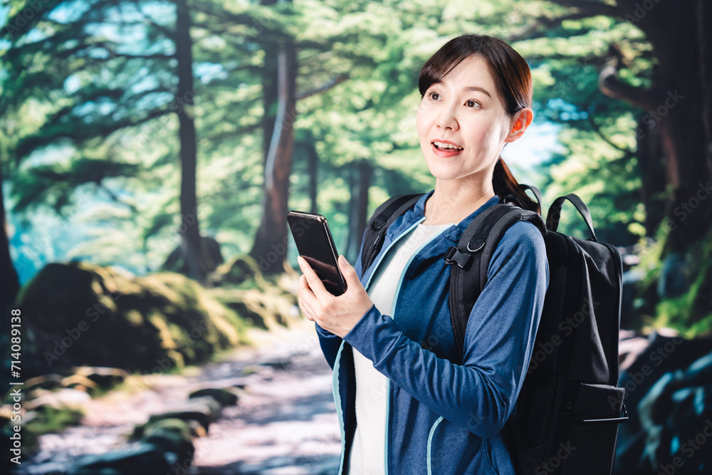ハイキングをしながらスマホで写真を撮る若い女性 ハイキングをしながらスマホで写真を撮る若い女性