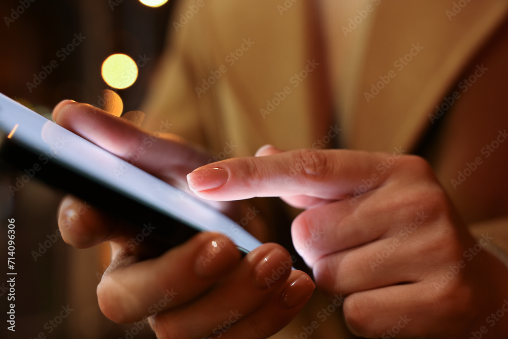 Woman using smartphone on blurred background, closeup