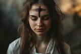The symbol of a cross made of ashes on praying woman's forehead for Ash Wednesday