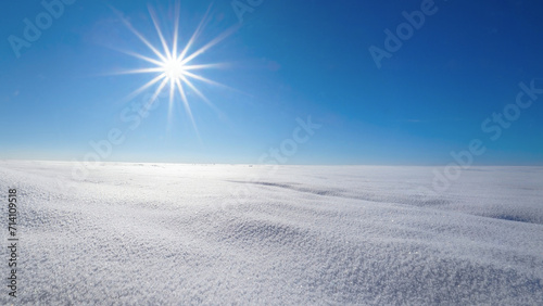 Winter landscape of untouched snow with blue sky and sun star