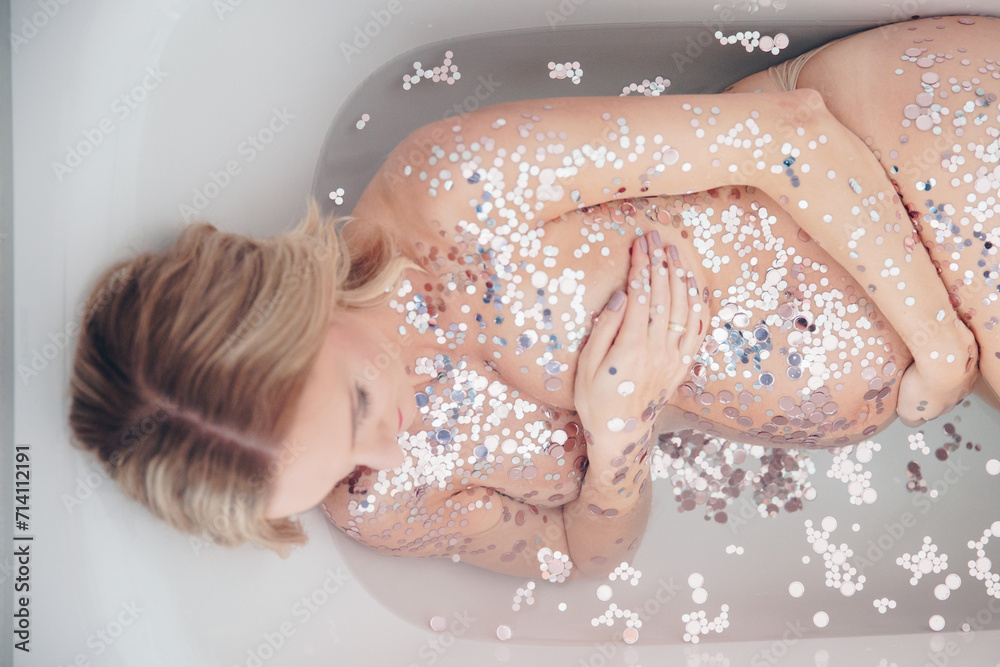 Fototapeta premium Schwangere in Badewanne mit Glitzer, Wohlbefinden, Fruchtbarkeit, ungeborene Gesundheit. Konzept Schwangerschaft, Mutterschaft, Gynäkologie