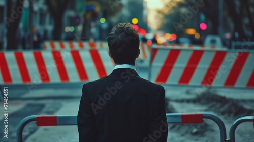 A determined businessman in a suit stands halted before a symbolic barrier, representing obstacles such as sanctions, economic challenges, or a potential business deadlock.