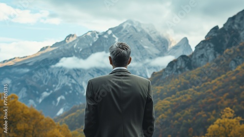 businessman in a suit stands at the base of a towering mountain  symbolizing the significant challenges and obstacles he faces in his career.