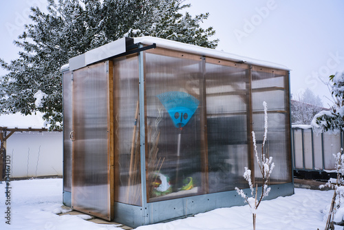 Snow-covered and transparent garden shed.