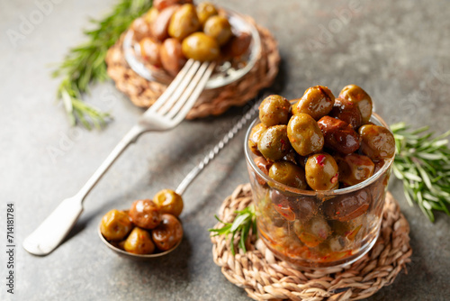 Spicy olives in a glass bowl on a stone table.