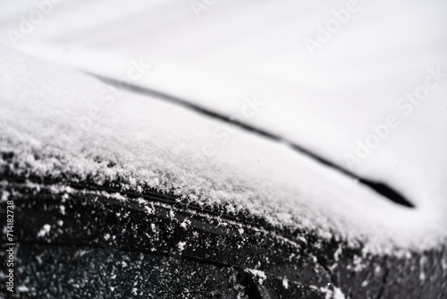 pare-brise, capot et porte de voiture noire sous la neige, en gros plan photo