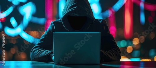 Anonymous hacker using laptop for cybercrime and hacking.