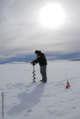 Ice fisherman drilling a hole