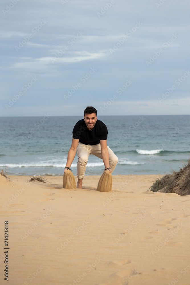 Barefoot man playing with sand on the beach Barefoot man playing with sand on the beach