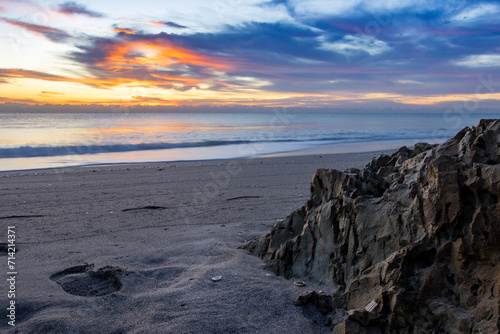 Wallpaper Mural Breathtaking sunset over a peaceful beach, with footprints in the sand and rocky formations. Perfect for travel, nature, and relaxation themes in wall art, home décor, or marketing materials. Torontodigital.ca