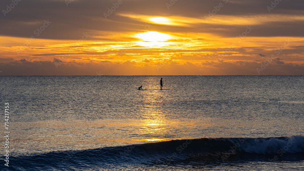 Paddle-boarders at sea during a captivating sunrise, perfect for adventure sports marketing, lifestyle editorials, and travel inspiration.