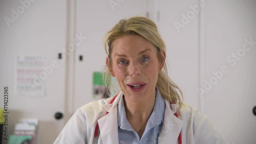 A blond, female doctor in blue scrubs consults a virtual patient over laptop, he discusses symptoms and then prescribes medicine. 
