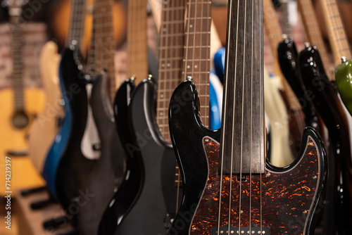 Closeup of row of different colorful bass guitars on the display for sale hanging in a music shop  photo