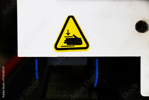 Safety label explaining that hands should be kept away from the pressing part of the machine. Work safety