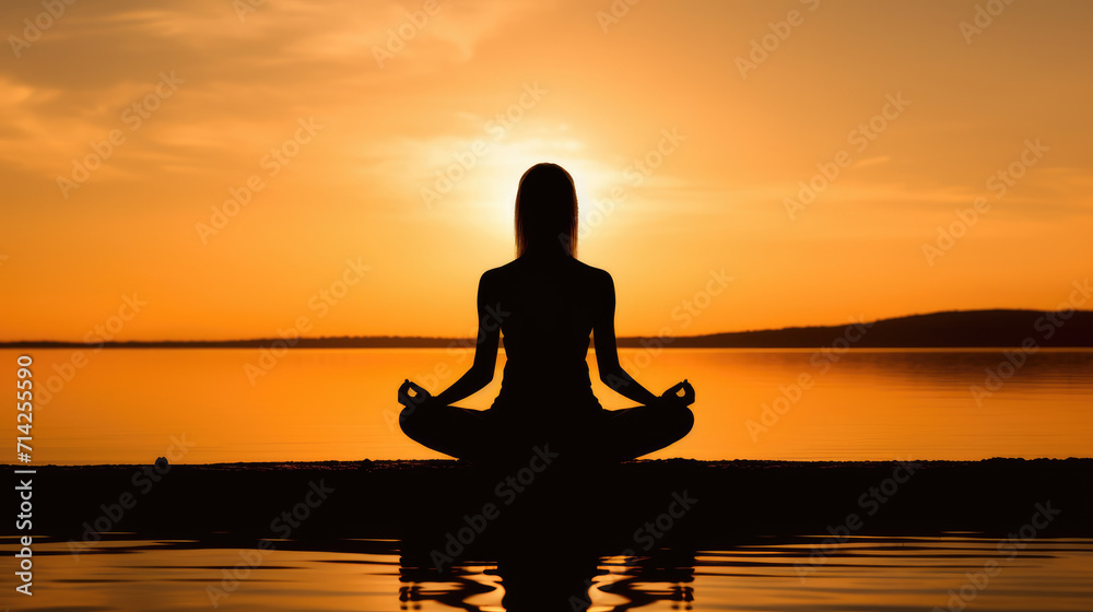Silhouette of woman practicing yoga for meditation against the sea at sunset