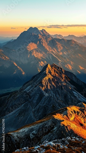 A breathtaking mountain range under the spell of sunset, with the sky in a gradient of orange to blue and the peaks highlighted in golden light