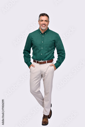 Confident elegant middle aged business man entrepreneur, smiling older professional stylish businessman wearing green shirt looking at camera standing isolated on gray, full length vertical portrait.