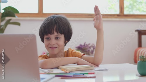 Happy boy raises his hand and prepares to answer in class, during video call for e-learning, education or virtual classroom introduction at home. online learning at home photo