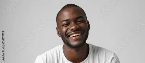 A young man's genuine smile radiates joy, his eyes sparkling with positivity against a crisp white backdrop