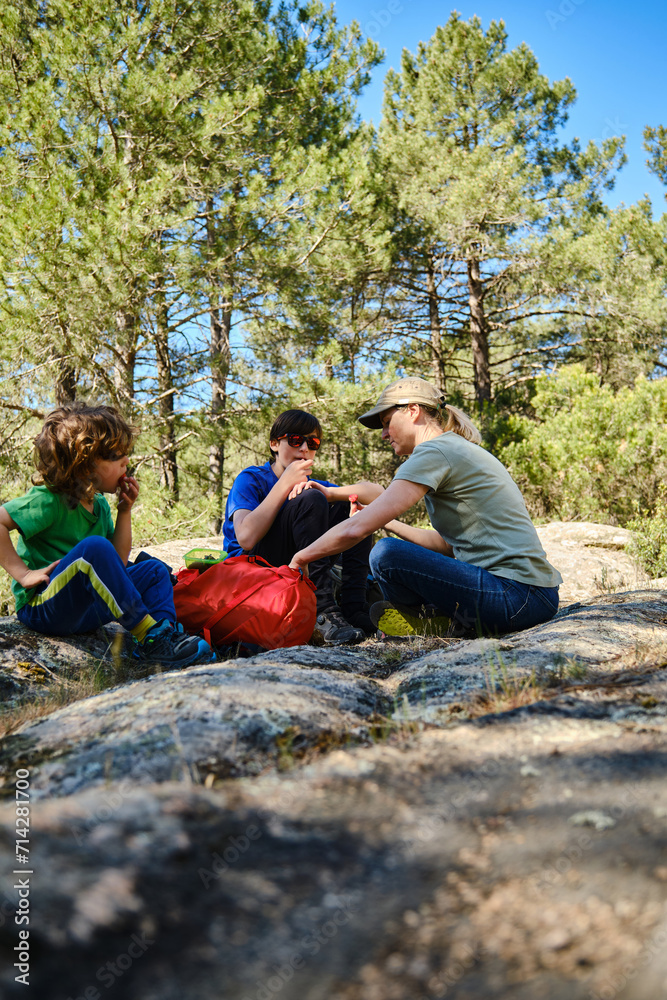 Focused family members eating while sitting on rocky terrain in forest Focused family members eating while sitting on rocky terrain in forest