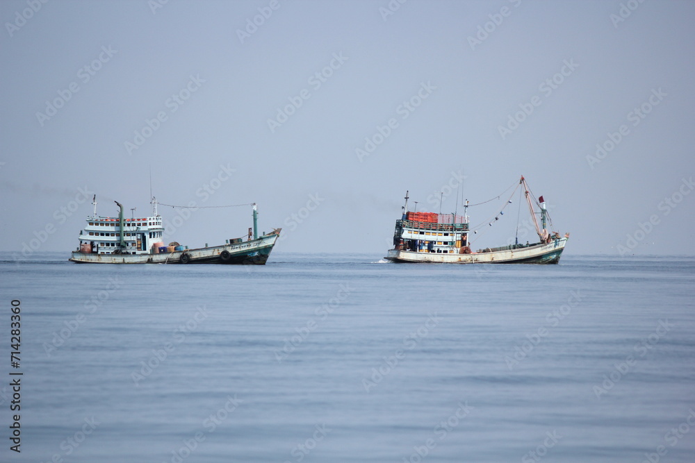 Fishing boats navigating the sea in a vibrant harbor, surrounded by the blue ocean, under a clear sky, symbolizing the maritime industry and transportation