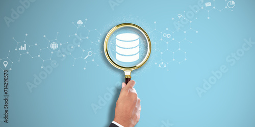 Database Management: Businessman Hand Holding a Magnifying Glass with Database Icon on Light Blue Background. Efficient Data Retrieval, Seamless Integration, Streamlined Operations.