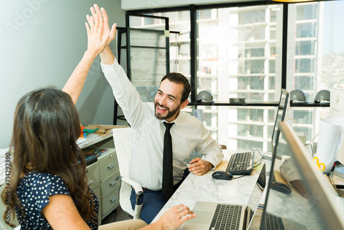 Businessman celebrating success with one of his coworkers and giving a high five in the office