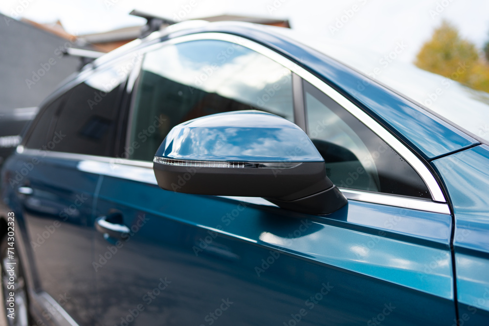 Close up view of mirror on outside of car passenger door on high-trim vehicle. Image formed in reflecting surface giving wide field of traffic view