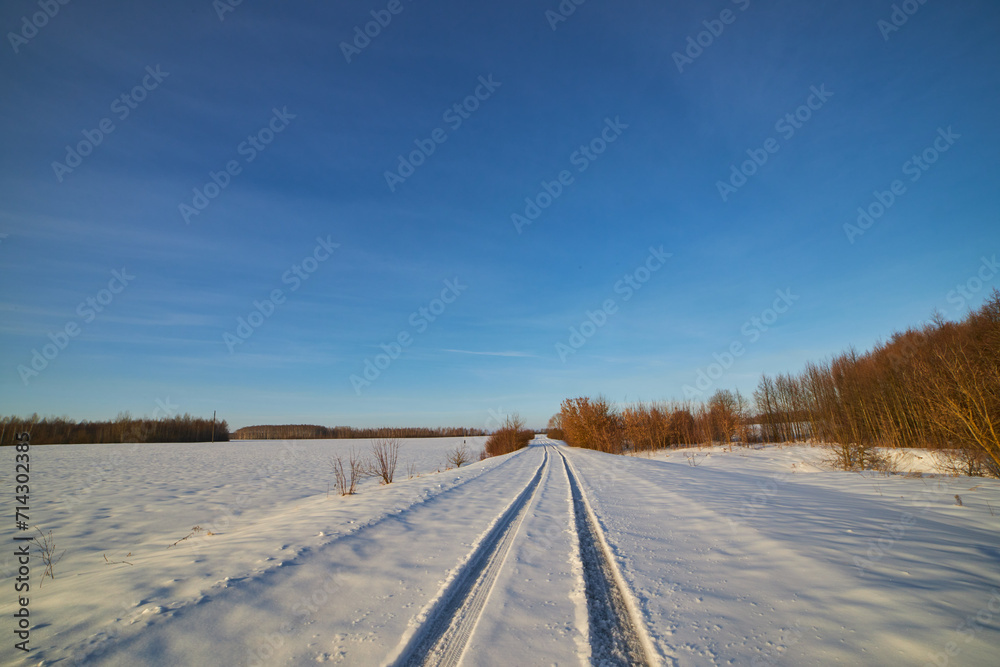 The first trace of a car in the snow along a country road.