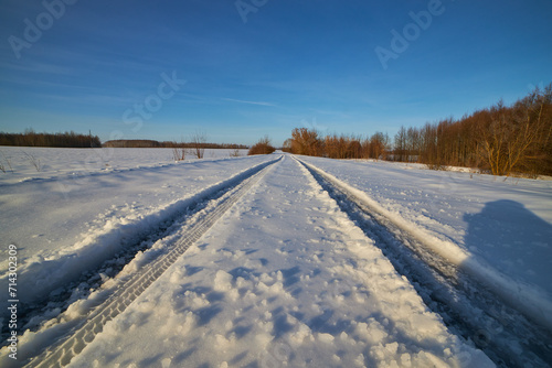 The first trace of a car in the snow along a country road.